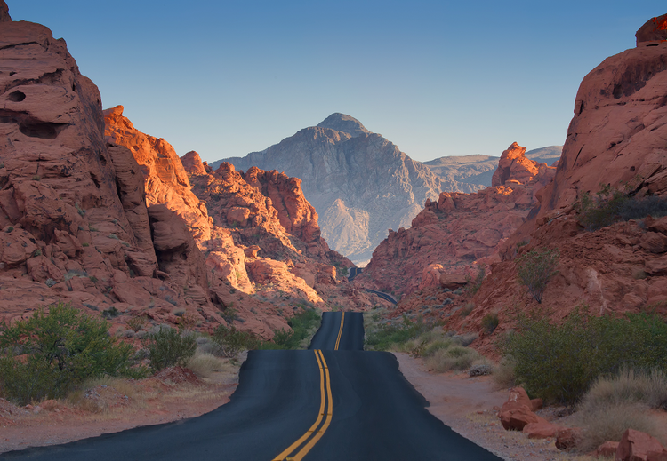 Scenic desert road with red rock formations on either side