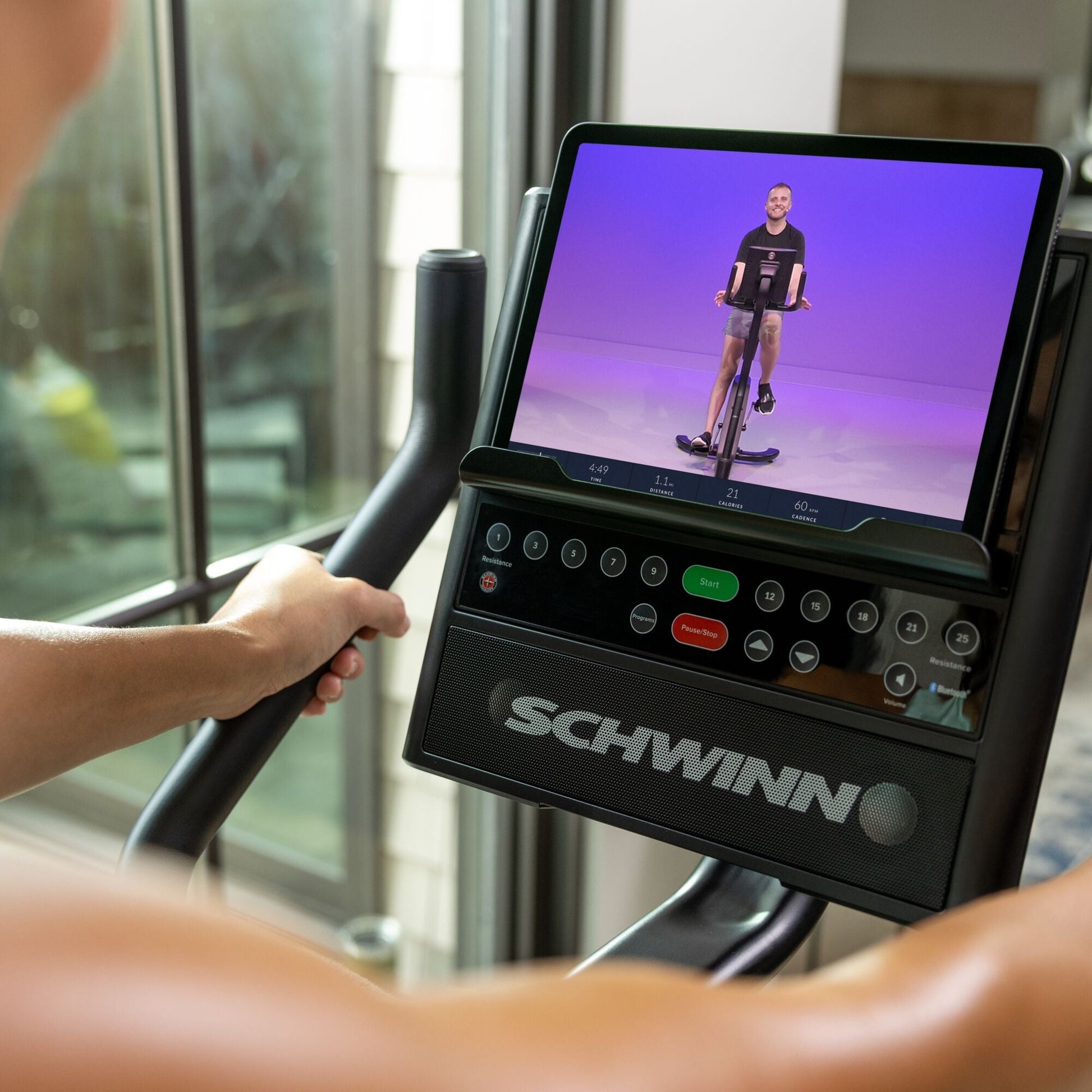 JRNY app screen on a tablet resting on the Schwinn 590U Upright Bike console.