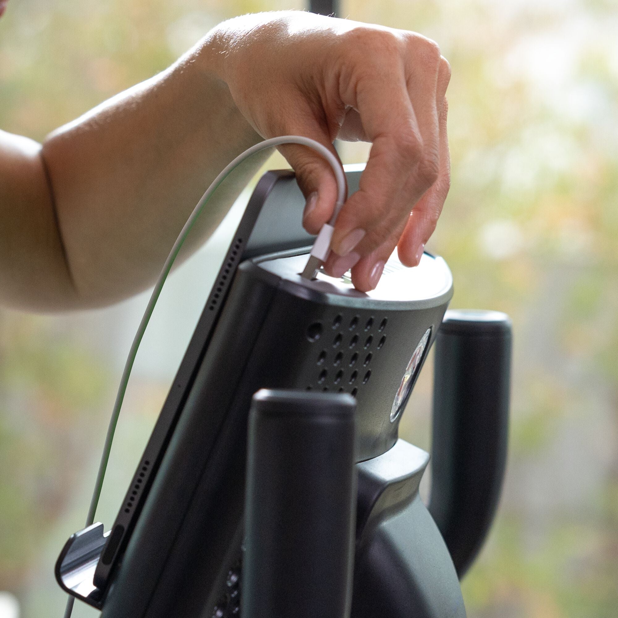 Hand plugging USB cord into the Schwinn 590U Upright Bike console.