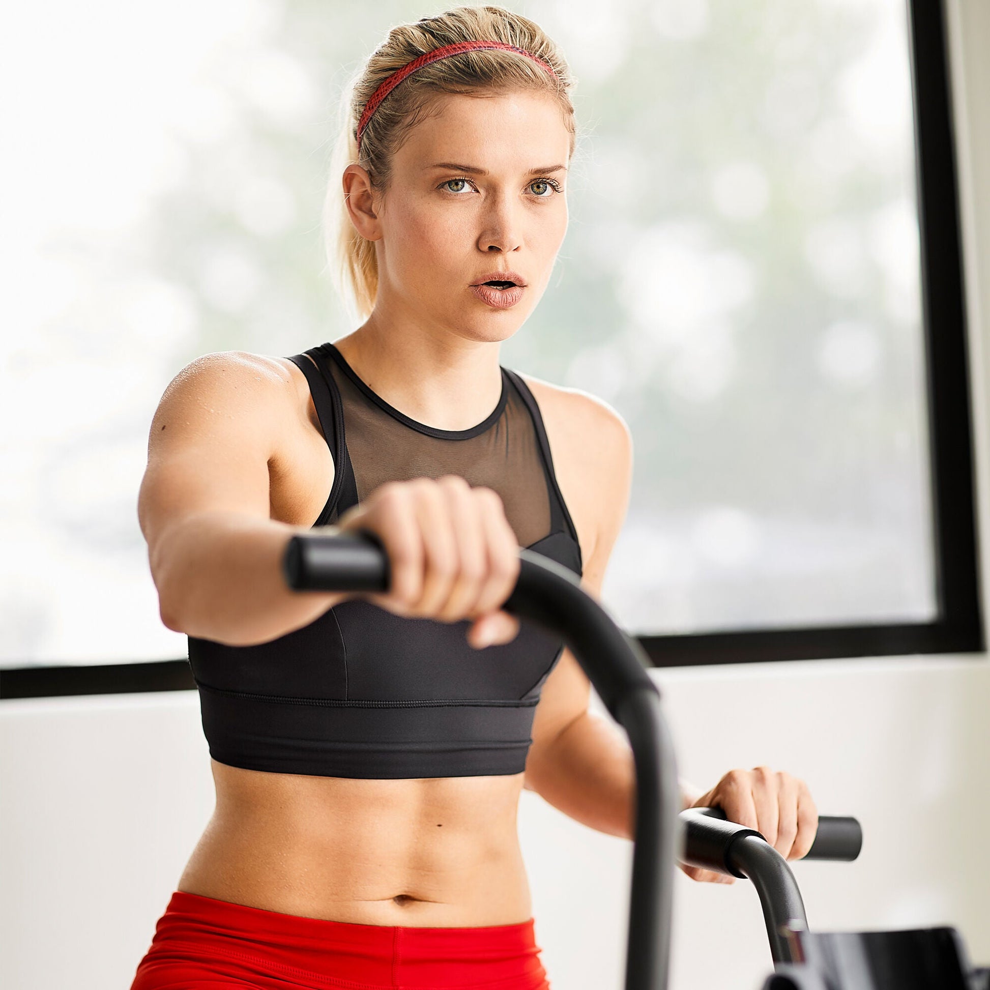 Close up of woman exercising indoors with her hands on the Schwinn Airdyne AD6i handlebars.