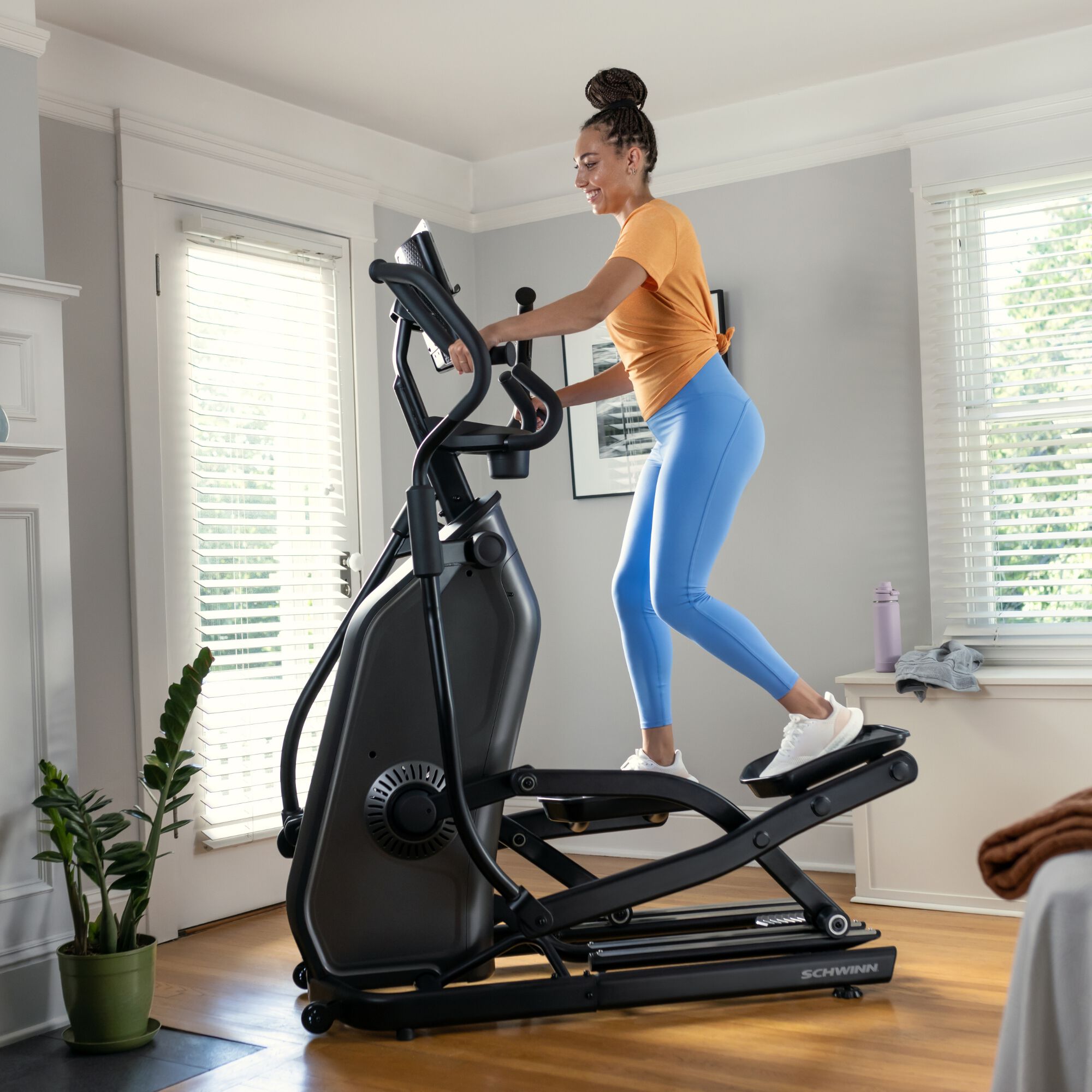 Woman using the Schwinn 590E Elliptical in a home setting.