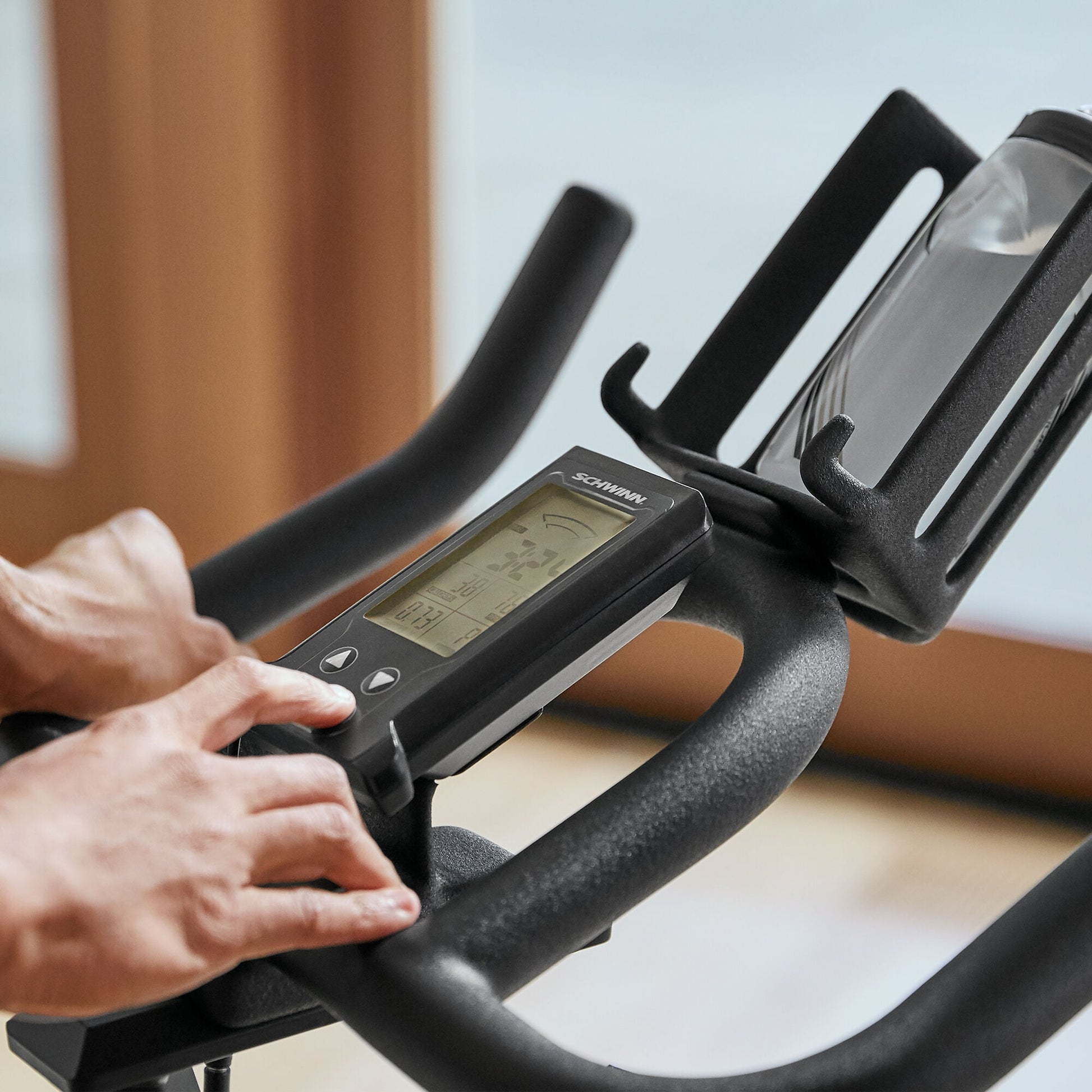 Person tapping a button on the Schwinn 700IC Indoor Cycling Bike console.