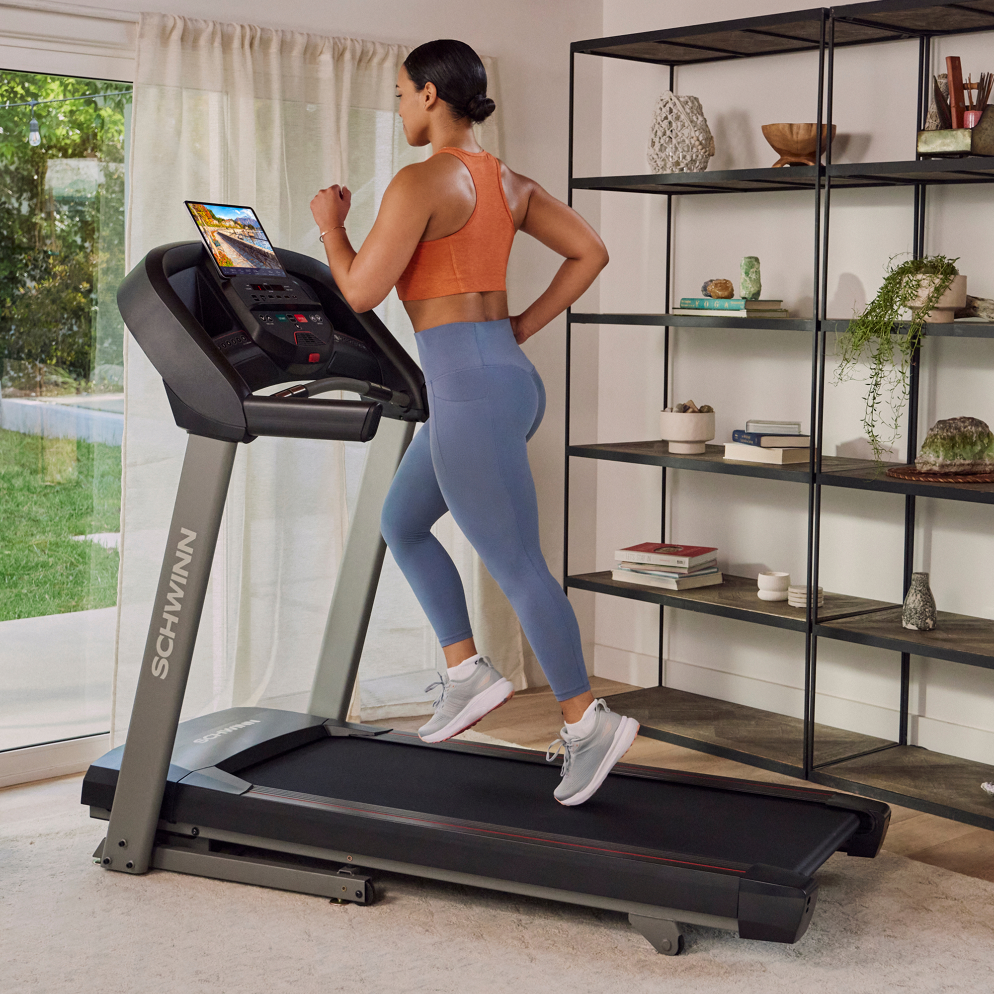 Woman using Schwinn SFT4.1 Treadmill in living room.