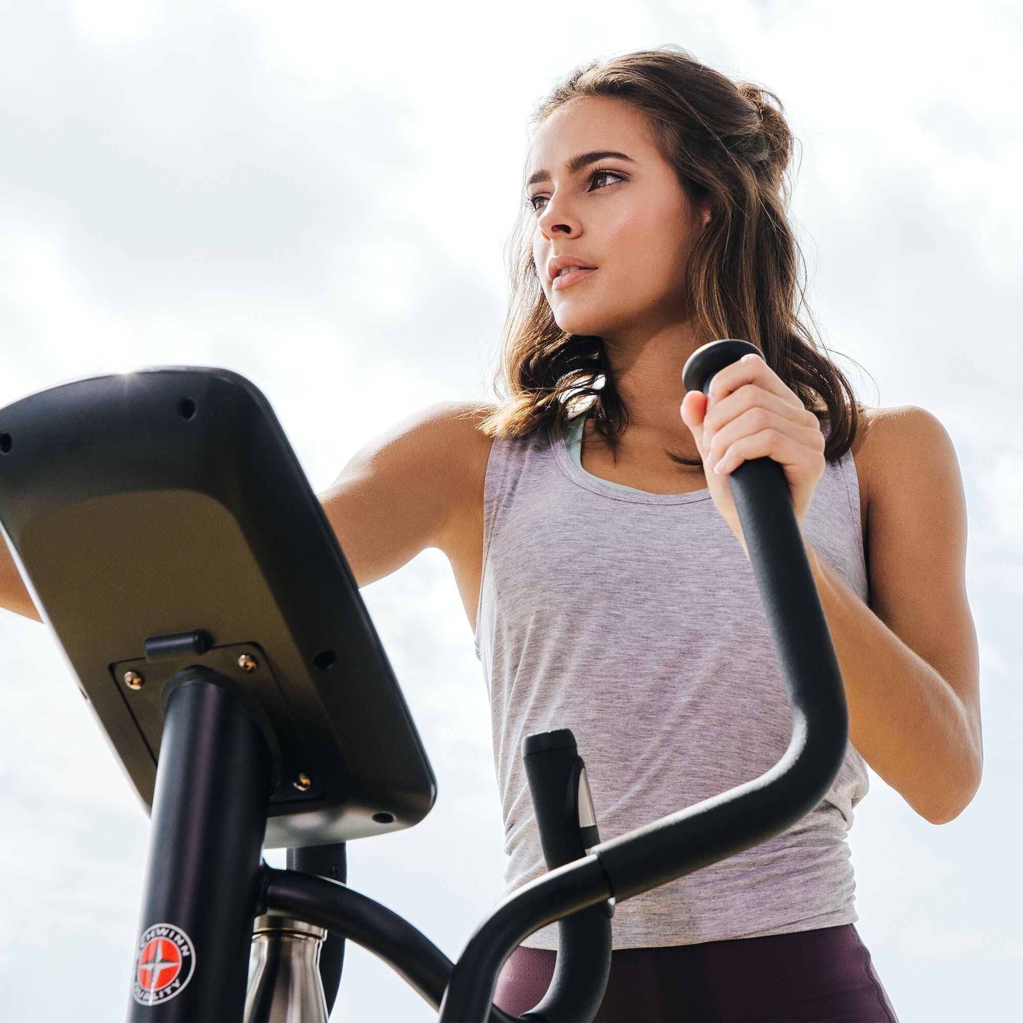 Woman using the Schwinn 510E Elliptical with the sky in the background.